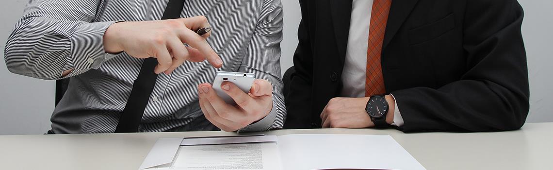 Work colleagues pointing to phone discussion 